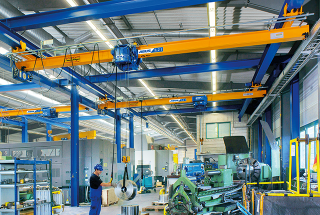 Grue a carroponte ABUS in un capannone industriale con portata fino a 8 t e luce fino a 25 m per il trasporto di materiali con un ingombro ridotto.