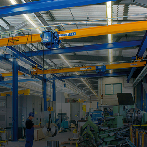 Grue a carroponte ABUS in un capannone industriale con portata fino a 8 t e luce fino a 25 m per il trasporto di materiali con un ingombro ridotto.