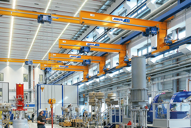 Carroponte monotrave a muro ABUS in un capannone industriale con portata fino a 5 t e luce fino a 12 m per un servizio efficiente di più postazioni di lavoro.
